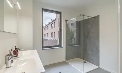 ruime badkamer in afgewerkt appartement - douche en dubbele lavabo, minimale inkijk maar veel lichtinval