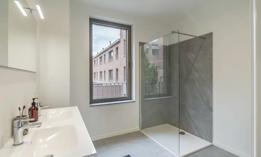 ruime badkamer in afgewerkt appartement - douche en dubbele lavabo, minimale inkijk maar veel lichtinval
