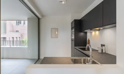 afgewerkt appartement in de heilig hartwijk - keuken met donkere materialen, veel lichtinval via het aangrenzende terras